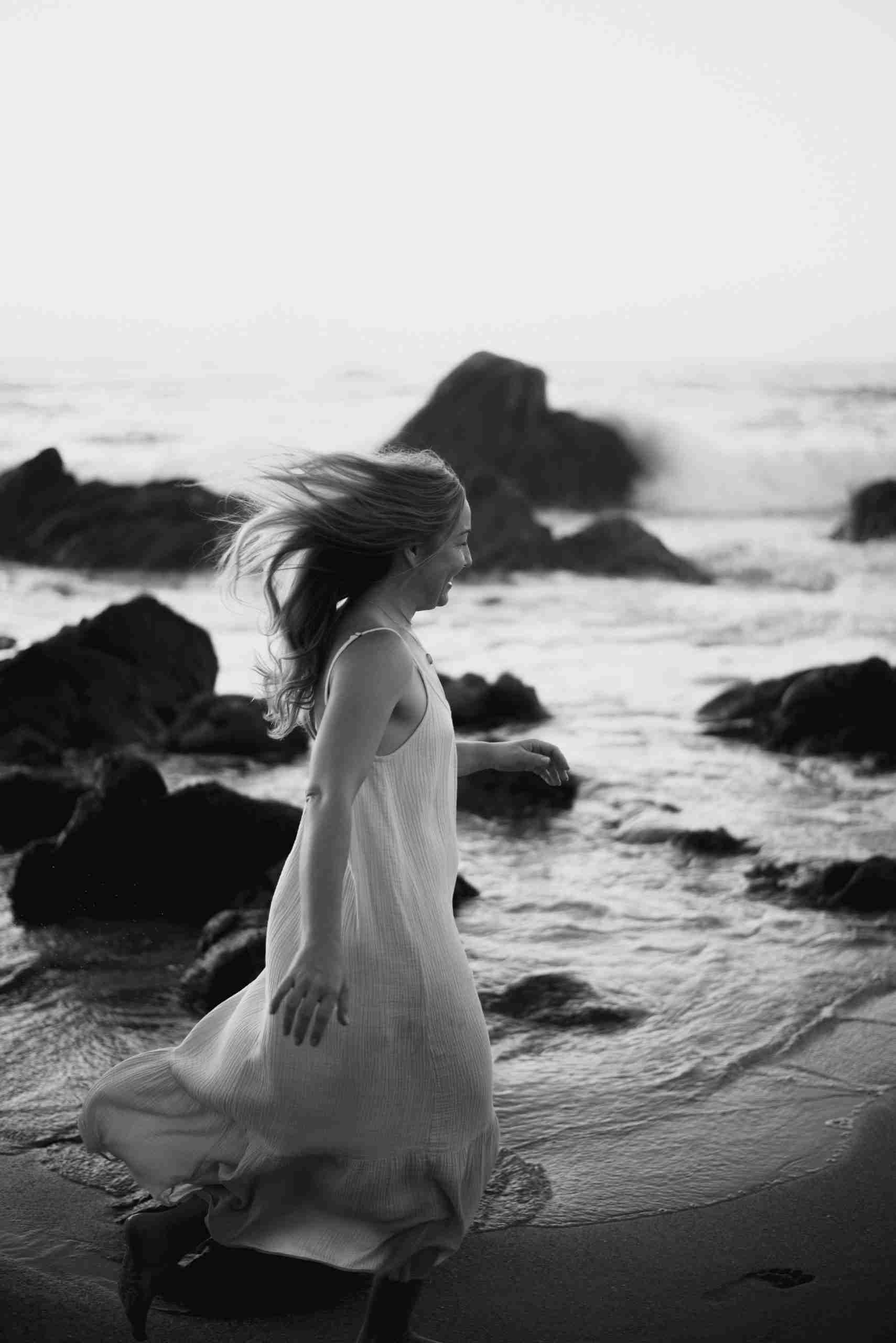 A woman laughing freely, hair in the wind by the ocean