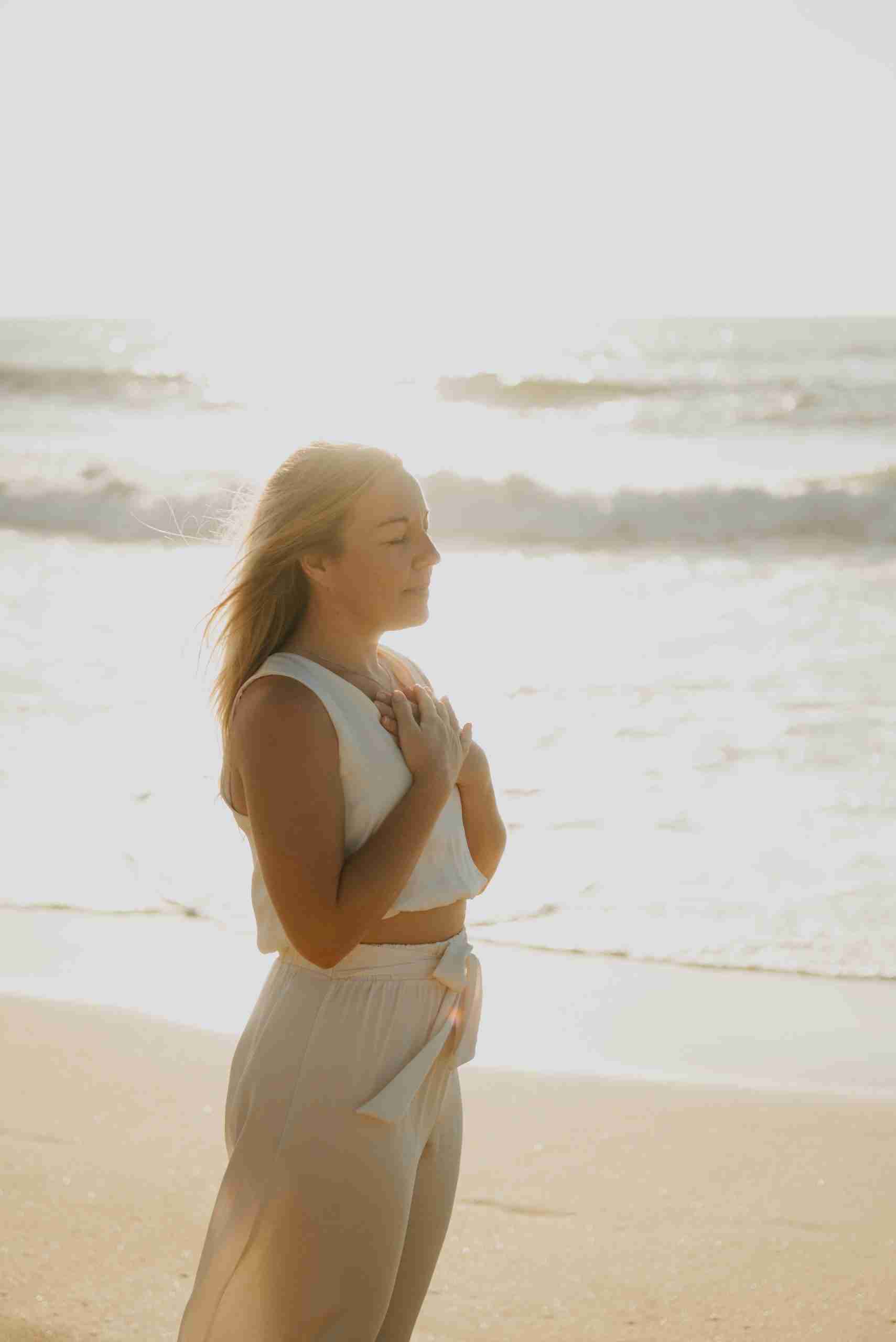 A woman with her eyes closed, hands resting gently over her heart